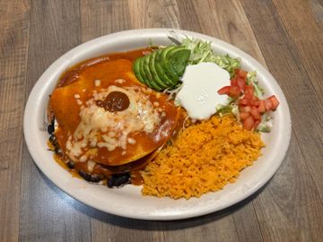 Enchiladas served with avocado and sour cream
