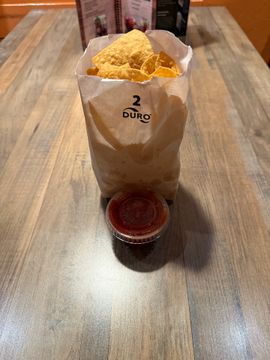 Bag of chips with salsa on table