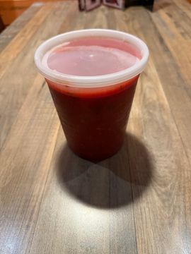 Red drink in takeaway plastic container.