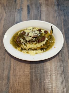 Steak with melted cheese and green sauce