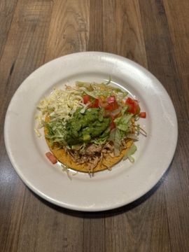 Tostada topped with vegetables and guacamole
