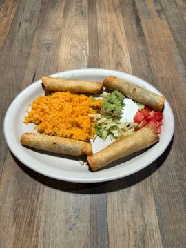 Plate of taquitos and colorful garnishes.
