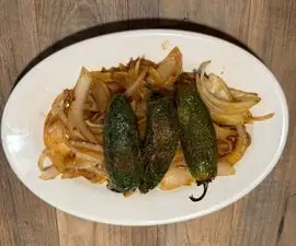 Three stuffed poblano peppers with sautéed onions