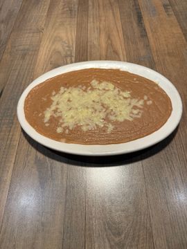 Cheesy refried beans on wooden table