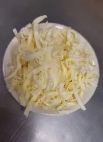 Bowl of shredded cheese on metal surface