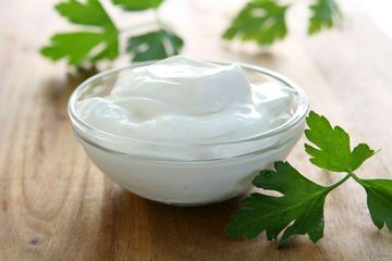 Bowl of creamy yogurt on wooden table