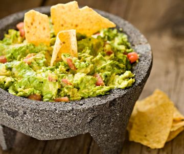 Guacamole in stone bowl with tortilla chips