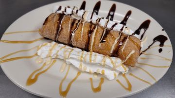 Pastry topped with whipped cream and sauce