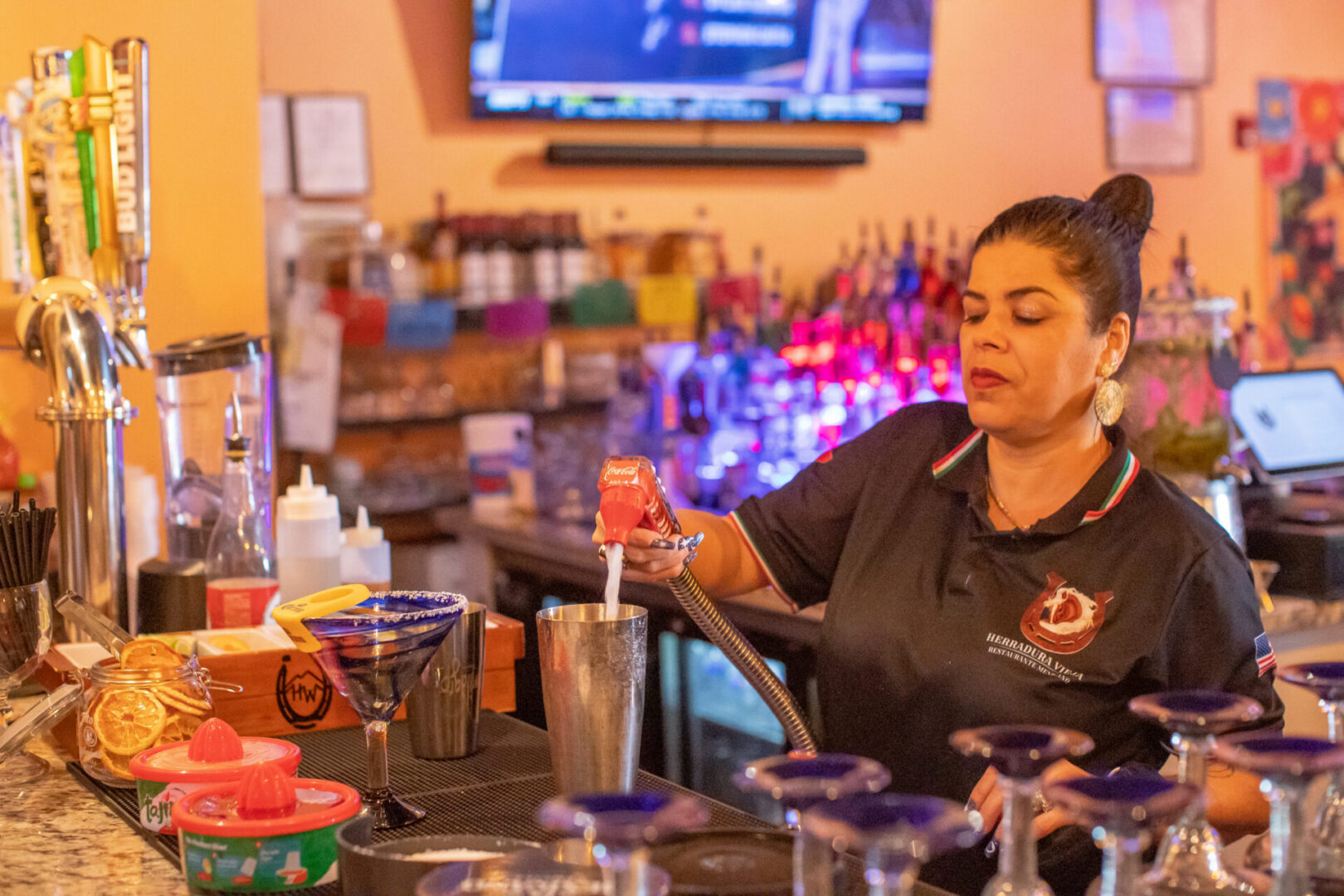 Bartender pouring cocktail into metal shaker