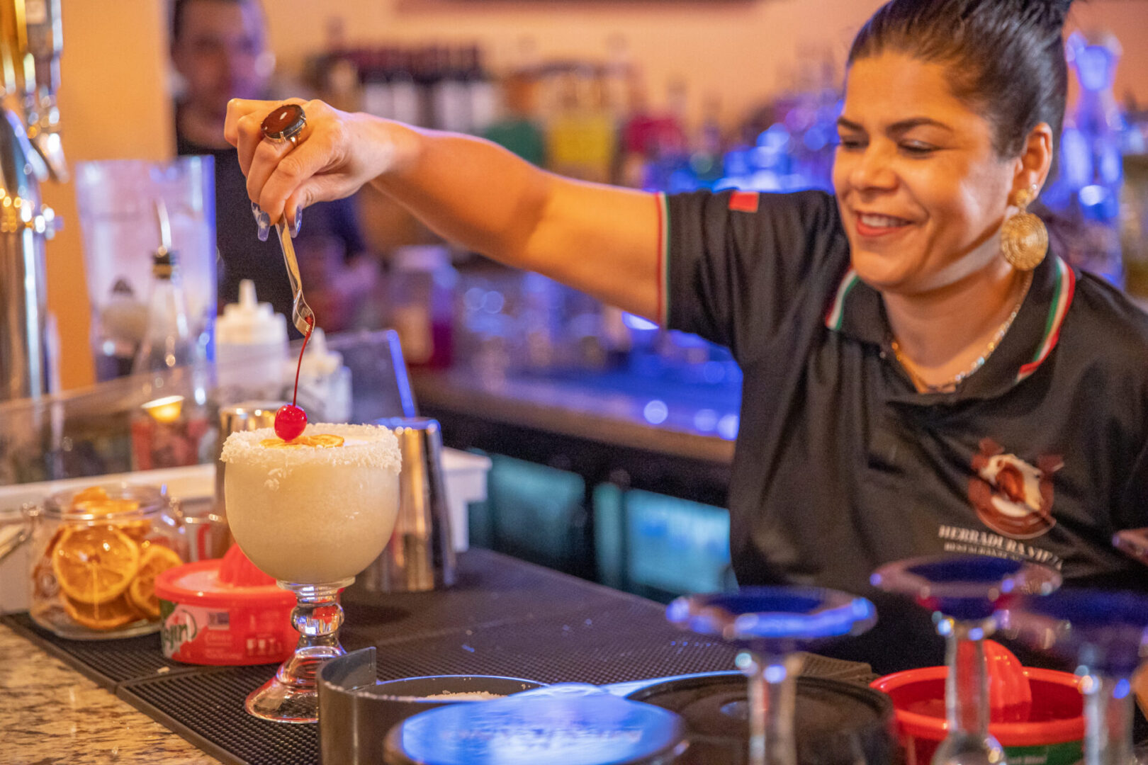 Smiling bartender garnishing frozen cocktail with cherry